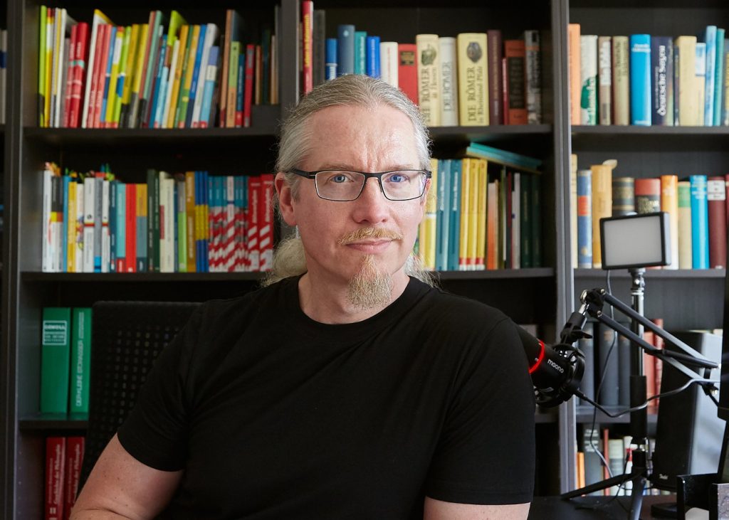 Dr. Stefan Schrumpf, Lerncoach (online und vor Ort) aus Bonn, in seinem Arbeitszimmer vor dem Bücherregal