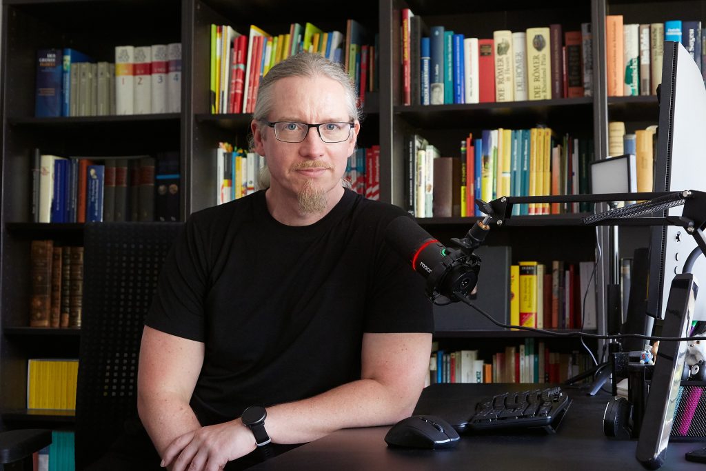 Dr. Stefan Schrumpf, Lerncoach (online und vor Ort) aus Bonn, an seinem Schreibtisch vor einem Bücherregal